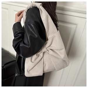Détail d'un sac fourre-tout en velours côtelé crème avec nœud sur une veste en cuir