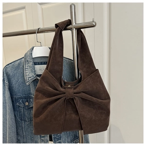 Detail of a dark brown hobo shoulder bag with a large bow in suede-like finish