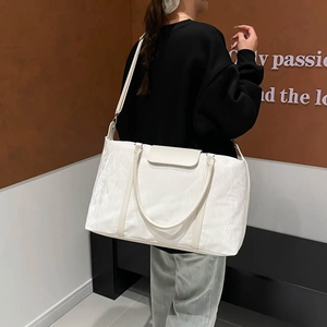 Large white travel bag with textured fabric and adjustable strap shown on model