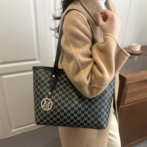 Chic black tote bag with gray M-pattern and gold metal charm for winter fashion outfits