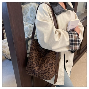 Détail du sac seau à imprimé léopard avec bandoulière en cuir porté sur un trench beige