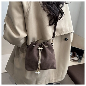 Détail du sac seau vintage en daim marron avec cordon doré et breloques en perles