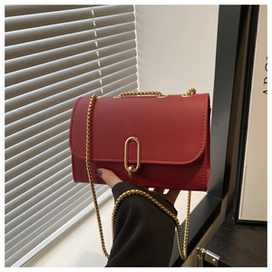 Detailed view of a red leather square bag with gold oval clasp and elegant chain strap