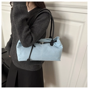 Detail of light blue canvas tote bag featuring black leather straps and hanging charm