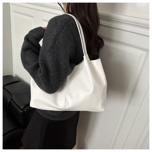Minimalist white leather tote bag shown on shoulder with sleek flexible texture