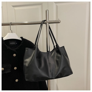 Close-up of black PU leather tote bag with vertical stitching hanging on a rack