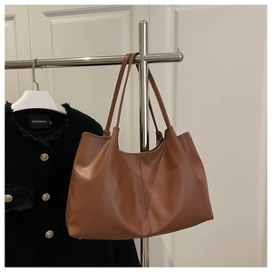 Close-up of caramel brown tote bag featuring vertical stitching and matte faux leather texture