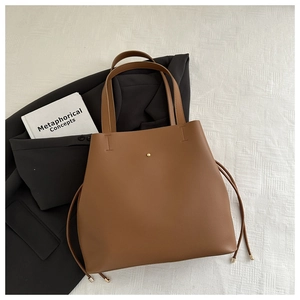 Detail of minimalist brown leather bucket bag with metal stud and drawstring on fabric