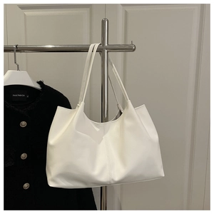 Detail of white leather tote bag featuring vertical stitching and minimalist slim handles