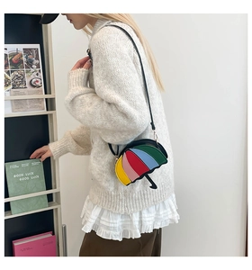 Detailed view of creative rainbow umbrella crossbody bag paired with white knit sweater