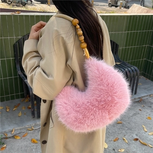 Sac hobo en fausse fourrure rose avec bandoulière en perles de bois porté par un modèle