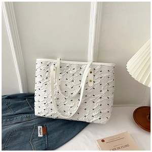 Vue détaillée du sac cabas blanc avec texture plissée et motifs de nœuds noirs chic