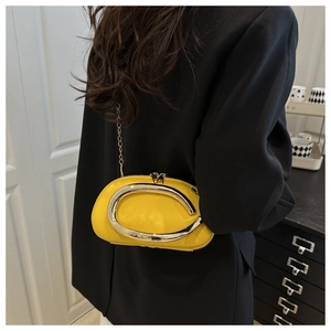 Detail of a bright yellow bean-shaped leather bag with a silver horseshoe metal handle