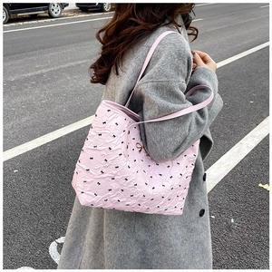 Détail du sac cabas plissé rose avec motifs nœuds noirs et pendentif doré chic