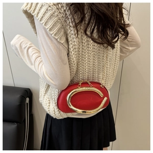 Detailed shot of red leather crossbody bag with gold C-shaped buckle on female model