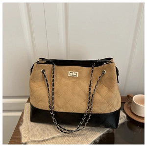 Detail of quilted suede tote bag with metal chain strap and golden turn-lock closure