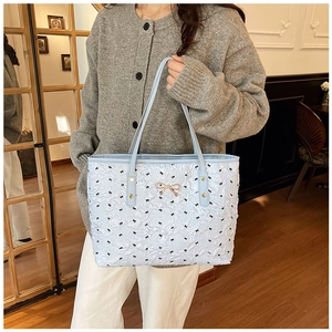 Détail du sac cabas plissé bleu clair avec imprimés nœuds et fermoir doré chic