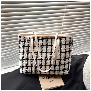 Close-up of black and white striped tweed tote bag with premium leather handles
