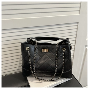 Detail of black quilted tote bag showing rhombus stitching and gold chain strap