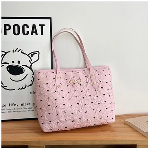 Détail du sac fourre-tout rose clair avec imprimé nœuds noirs et accessoire doré