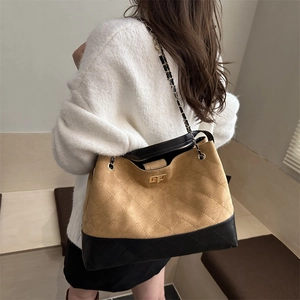 Quilted oversized tote bag with brown suede and black leather stitching on model