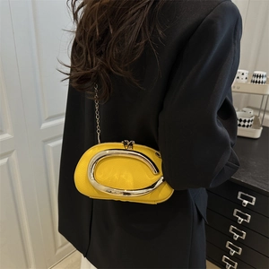 Yellow acrylic evening clutch with gold C-handle and chain strap on a black blazer