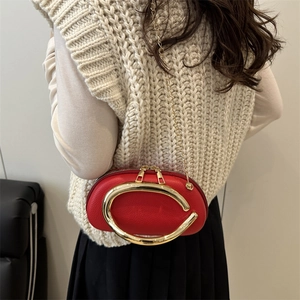 Red pebbled leather handbag featuring a large golden C-handle and metallic chain strap