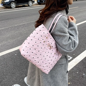 Sac fourre-tout rose à volants et motifs nœuds, porté avec un manteau d'hiver gris
