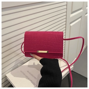 Detail showing fuchsia crocodile pattern leather bag with golden metallic bar and thin strap