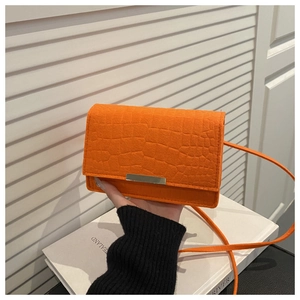 Close-up of bright orange faux leather bag with crocodile texture and silver metal clasp