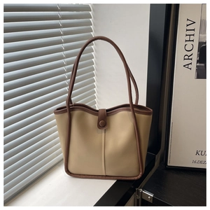 Detalle del bolso tote beige minimalista con ribete marrón y cierre de botón a presión