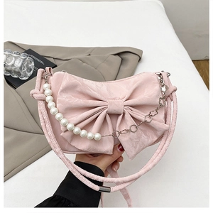 Detail of pink bow shoulder bag with white pearls and silver metal chain decoration