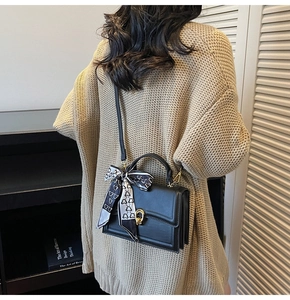 Détail du sac bandoulière noir avec foulard en soie décoratif porté par le mannequin
