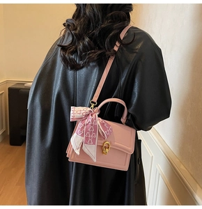 Sac à bandoulière rose avec chaîne et foulard à cœurs porté par un mannequin sur une veste