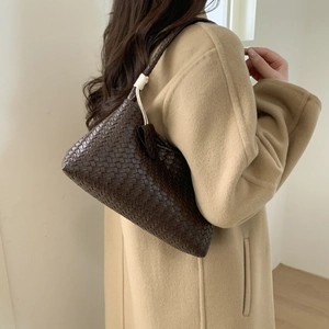 Détail du sac bandoulière en cuir tressé marron foncé avec poignée à nœud sur modèle