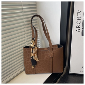 Détail d'un sac cabas rétro marron à motif léopard avec un foulard en soie sur l'anse