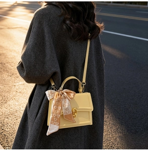 Détail d'un sac à bandoulière crème chic avec foulard à motif ours au coucher du soleil