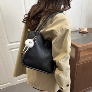 Classic black leather tote bag with plush charm shown on a model for daily commuting