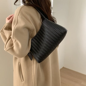 Gros plan du sac hobo tressé noir à la main montrant les détails du similicuir
