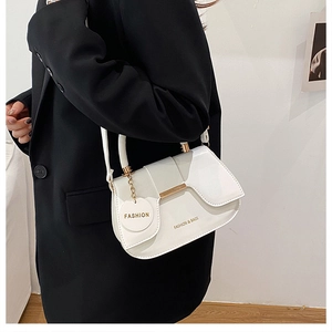 Dettaglio della borsa a sella in vernice bianca con finiture dorate su una modella