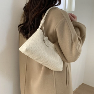 Détail du sac sous le bras en cuir tressé blanc avec nœuds décoratifs sur la bandoulière