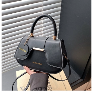 Dettaglio della borsa a sella in pelle nera opaca con hardware e ciondoli dorati Fashion