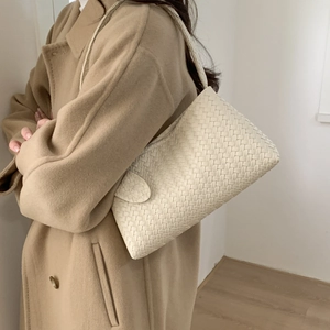 Chic beige woven hobo shoulder bag styled with a stylish cashmere coat in indoor setting