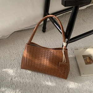 Close-up of woven leather texture on a caramel brown crescent shoulder bag for women