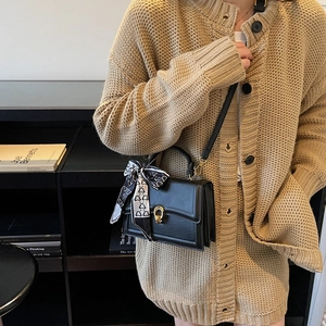 Sac à main élégant en cuir noir avec fermoir doré et détail de foulard en soie