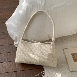 Detail of cream woven leather shoulder bag with intricate Intrecciato texture and strap