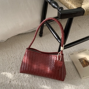 Close-up of the burgundy leather woven texture and artisan knot handle of this shoulder bag