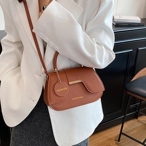 Borsa a sella marrone da donna con fibbia dorata in un ambiente elegante e minimale