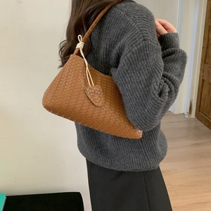 Sac cabas tissé main en cuir marron avec pendentif cœur et fines anses porté par modèle