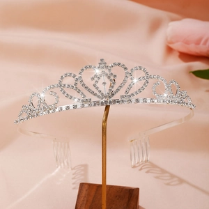 Sparkling silver rhinestone tiara with heart motifs and combs on pink silk background
